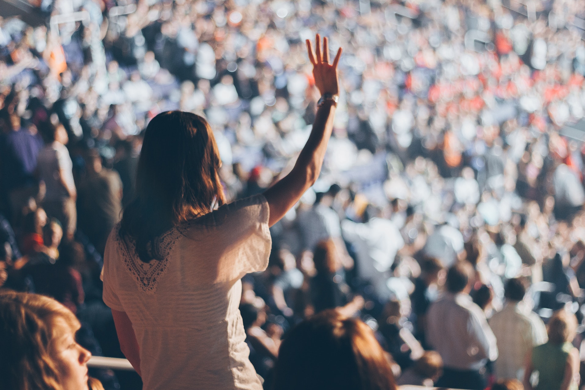 a large stadium audience in the background, a woman in a white top in the foreground